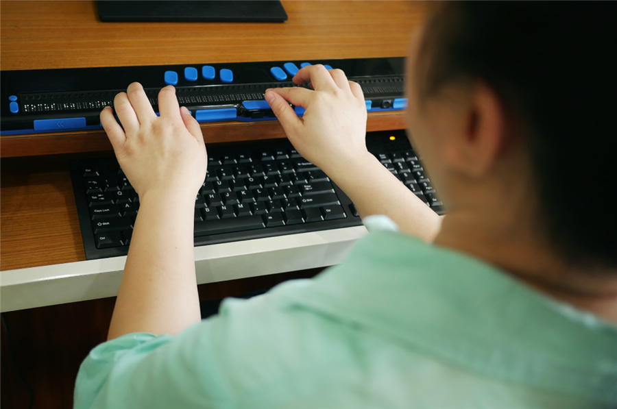 Foto van een persoon bij een toetsenbord voor mensen met een visuele beperking